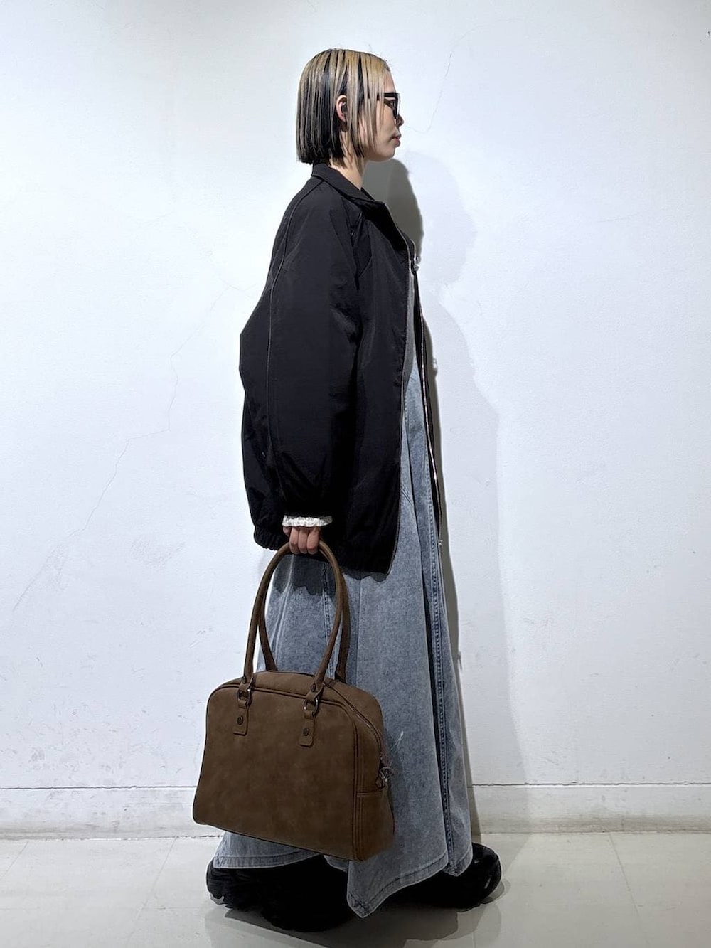 ブラック系のブーツ、ベージュ系のボストンバッグ、ブラック系のナイロンジャケットを着用したレディースの春コーディネートの3枚目の写真