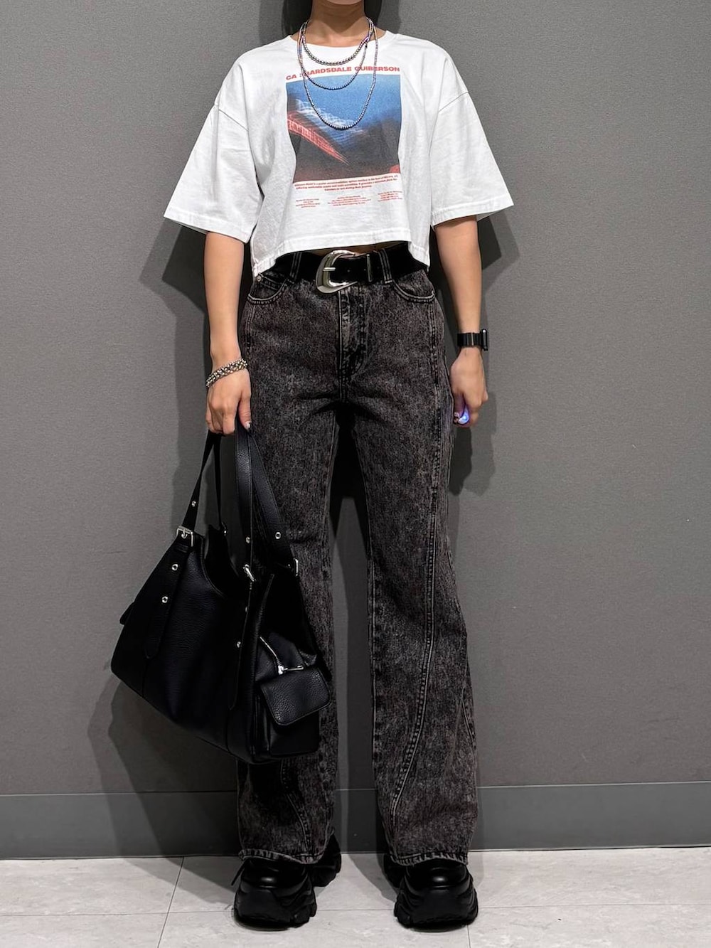 ブラック系のスニーカー、ブラック系のデニムパンツ、ホワイト系のTシャツ/カットソーを着用したレディースの春コーディネートの3枚目の写真