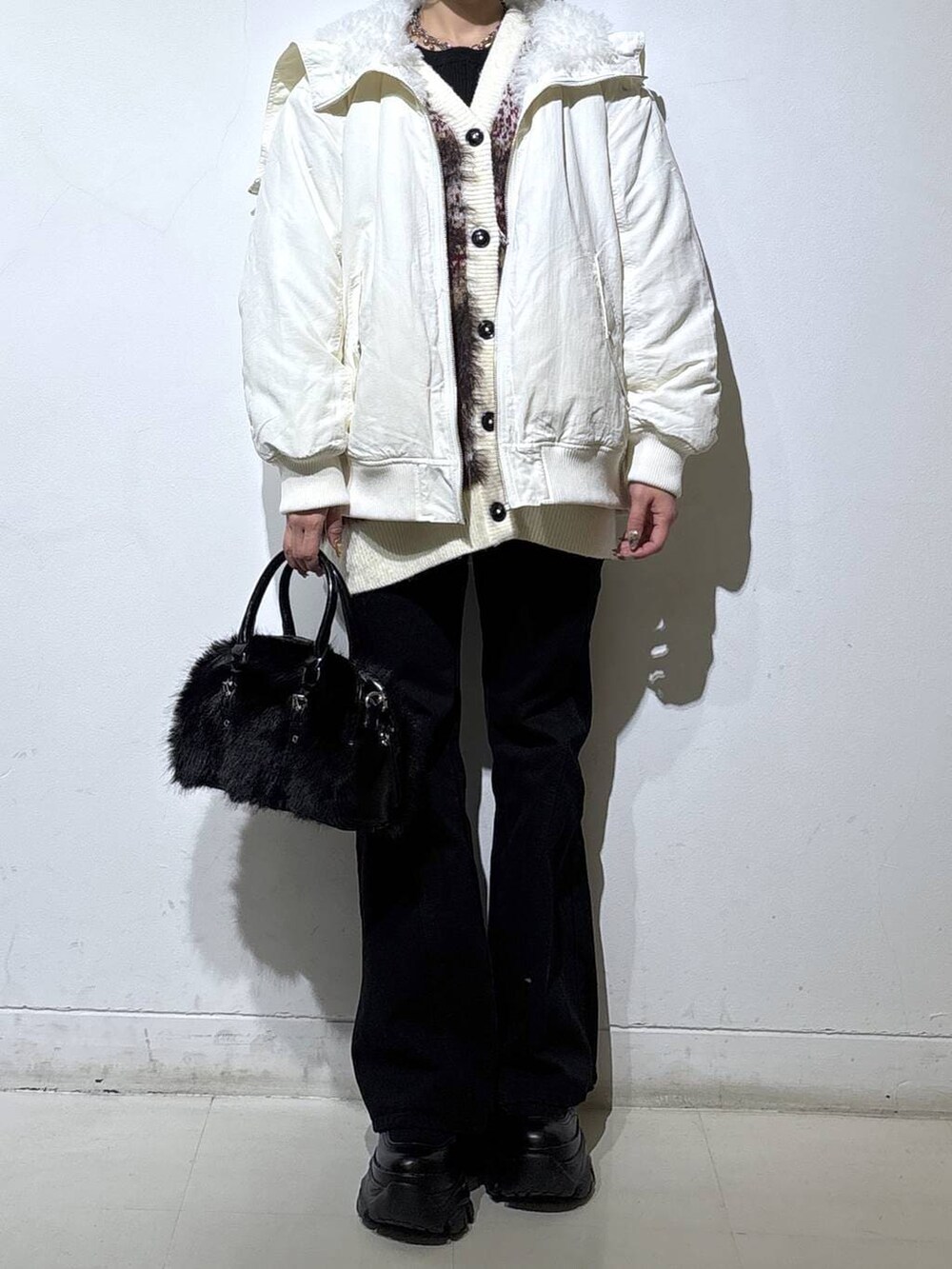 ブラック系のスニーカー、ブラック系のデニムパンツ、ホワイト系のブルゾンを着用したレディースの冬コーディネートの2枚目の写真