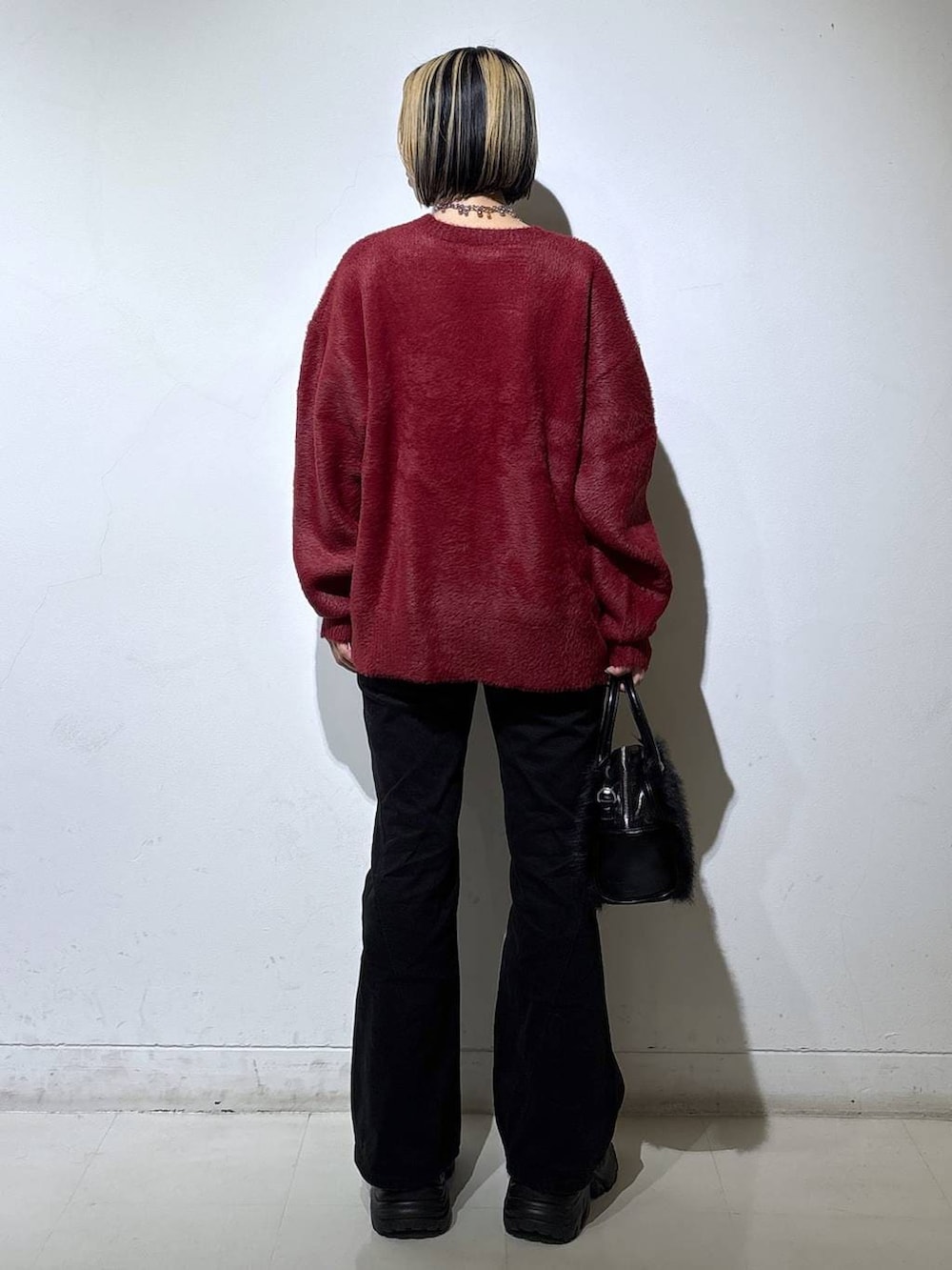 ブラック系のブーツ、ブラック系のデニムパンツ、レッド系のニット/セーターを着用したレディースの冬コーディネートの4枚目の写真