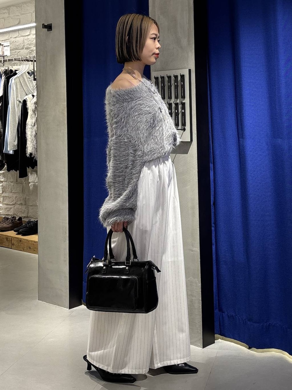 グレー系のニット/セーター、ブラック系のショルダーバッグ、ブラック系のサンダルを着用したレディースの冬コーディネートの4枚目の写真