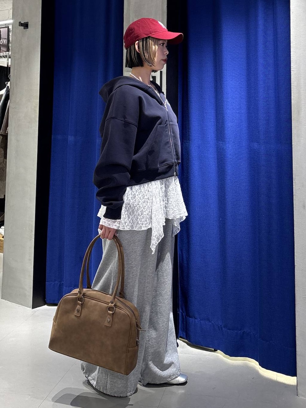 イエロー系のボストンバッグ、ブルー系のパーカー、グレー系のスウェットパンツを着用したレディースの冬コーディネートの5枚目の写真