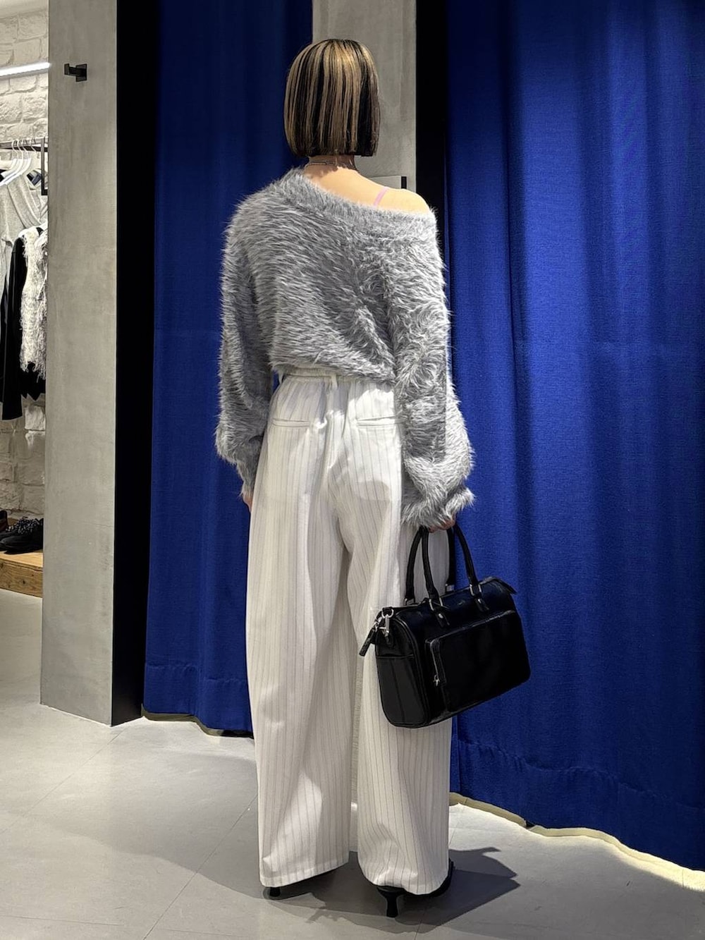 グレー系のニット/セーター、ブラック系のショルダーバッグ、ブラック系のサンダルを着用したレディースの冬コーディネートの5枚目の写真