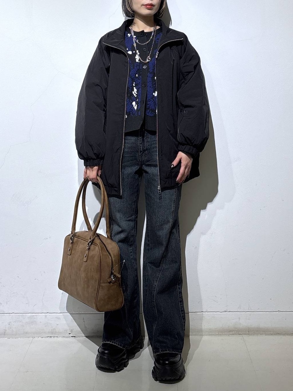 ブラック系のブーツ、ベージュ系のボストンバッグ、ブルー系のデニムパンツを着用したレディースの春コーディネートの2枚目の写真