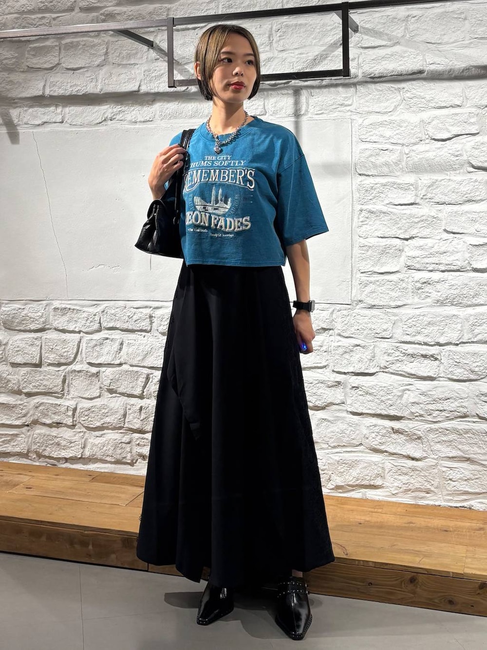 ブラック系のスカート、ブルー系のTシャツ/カットソー、ブラック系のショルダーバッグを着用したレディースの夏コーディネートの2枚目の写真