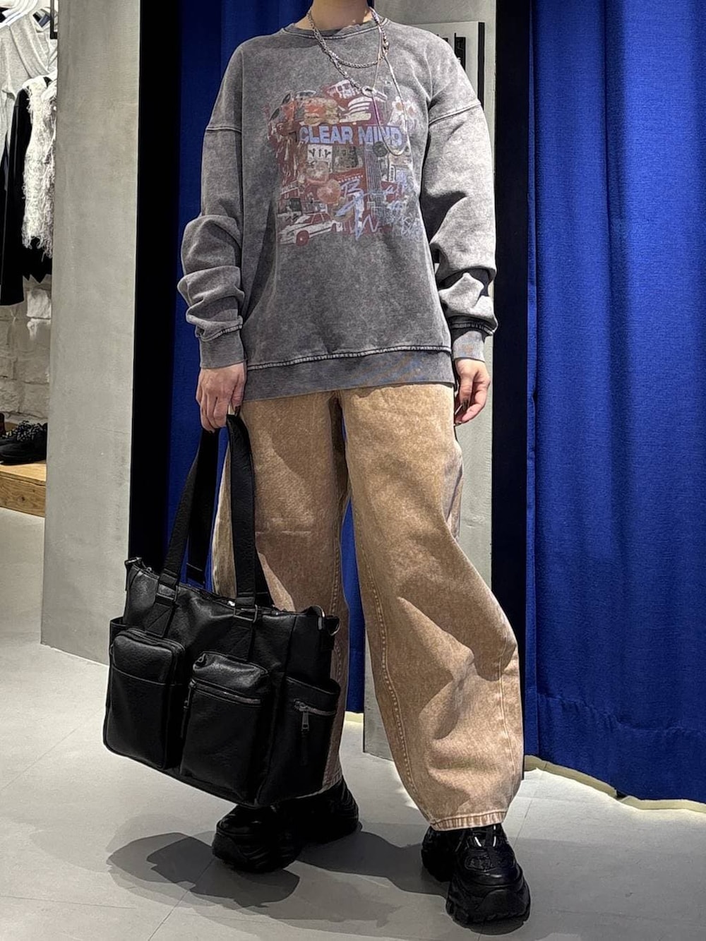 ブラック系のスニーカー、ブラック系のボストンバッグ、ブラウン系のデニムパンツを着用したレディースの冬コーディネートの2枚目の写真