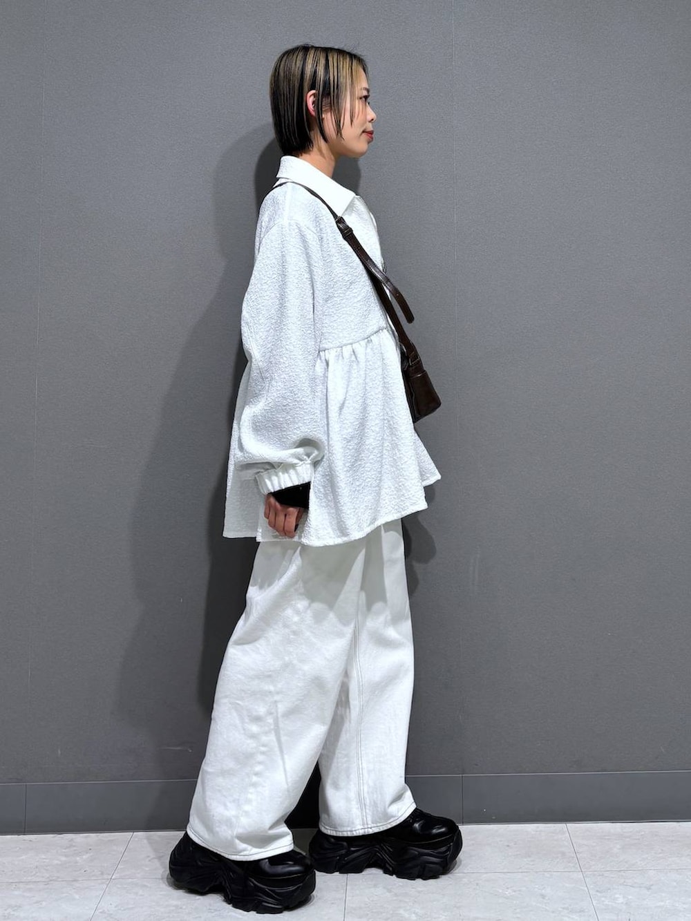 ブラック系のスニーカー、ホワイト系のスラックス、ブラウン系のショルダーバッグを着用したレディースの春コーディネートの4枚目の写真