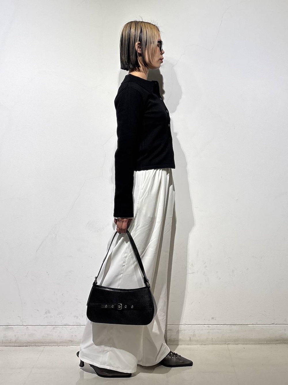 ブラック系のハンドバッグ、ブラウン系のサンダル、ホワイト系のスラックスを着用したレディースの冬コーディネートの3枚目の写真