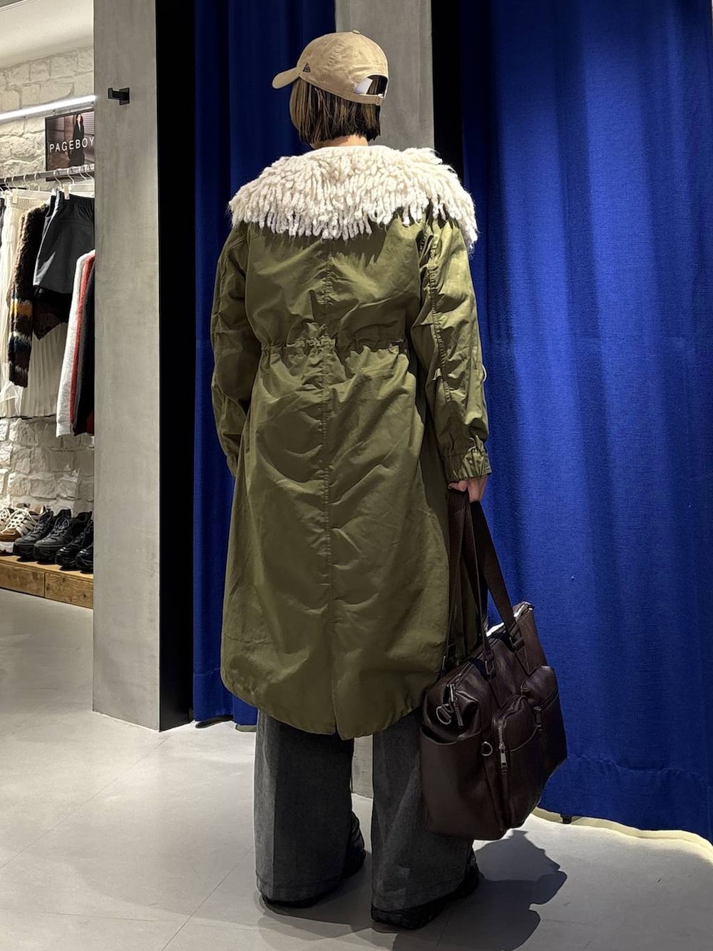 ブラック系のスニーカー、ブラウン系のボストンバッグ、ブラック系のニット/セーターを着用したレディースの冬コーディネートの4枚目の写真