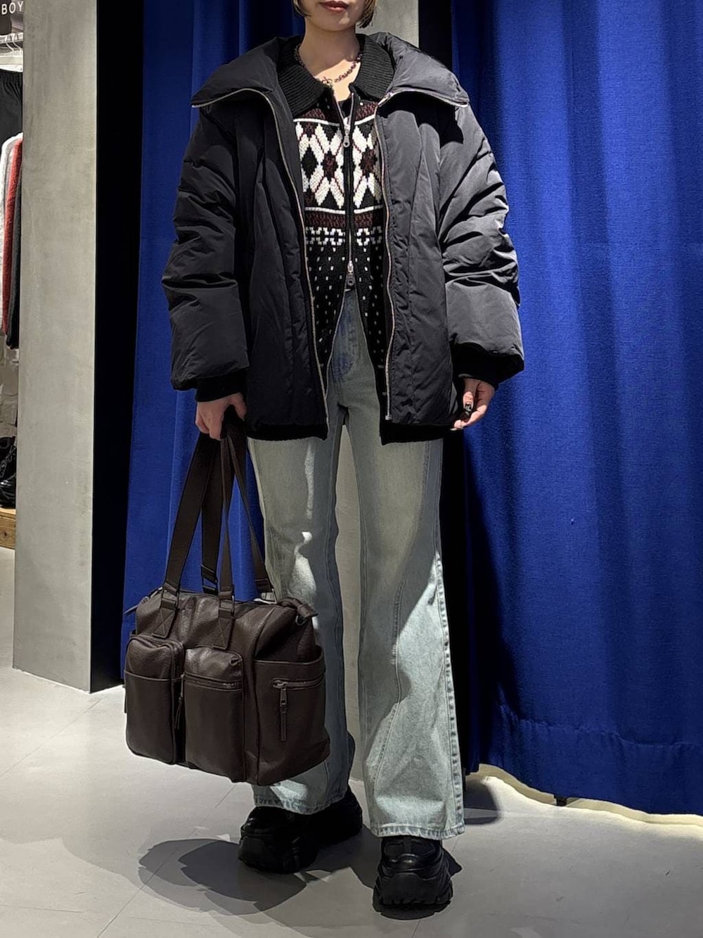 ブラック系のスニーカー、ブルー系のデニムパンツ、ブラウン系のボストンバッグを着用したレディースの冬コーディネートの2枚目の写真