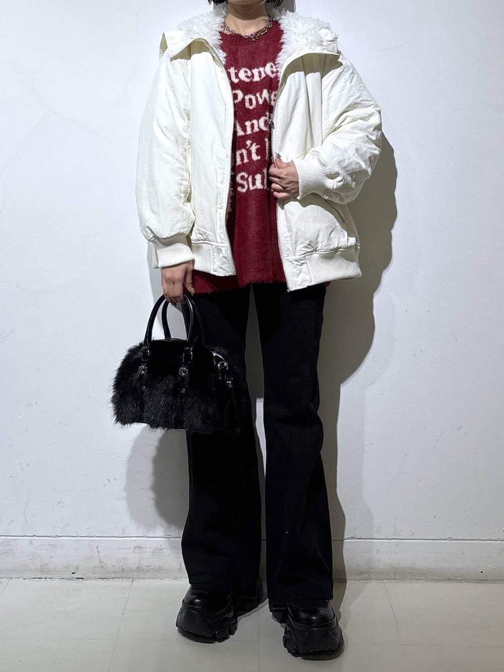 ブラック系のブーツ、ブラック系のデニムパンツ、ホワイト系のブルゾンを着用したレディースの冬コーディネートの2枚目の写真