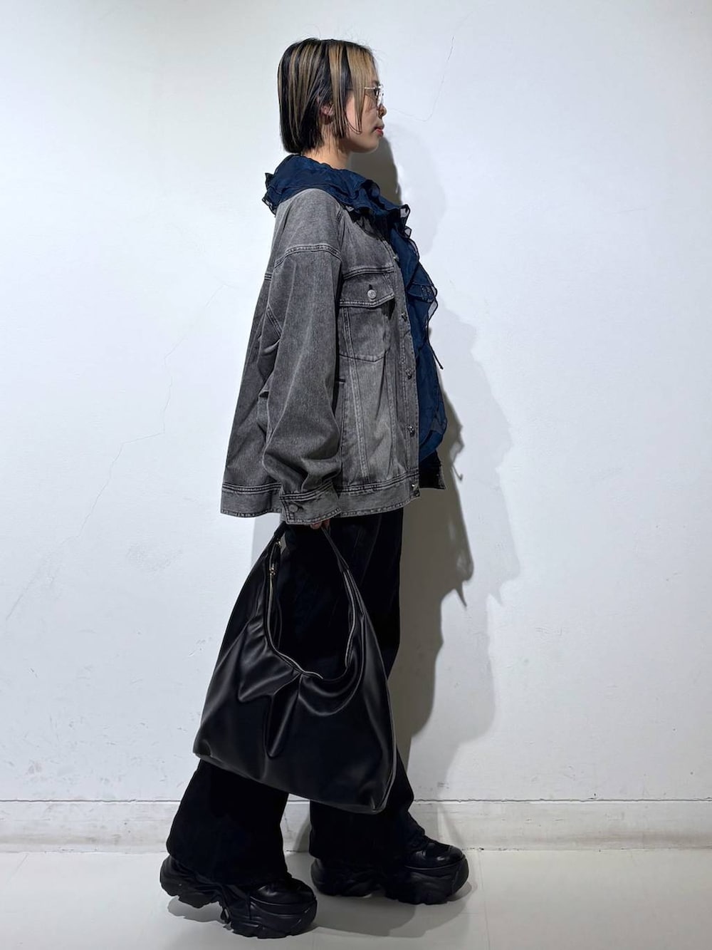 ブラック系のスニーカー、ブラック系のデニムパンツ、ブラック系のブルゾンを着用したレディースの春コーディネートの4枚目の写真