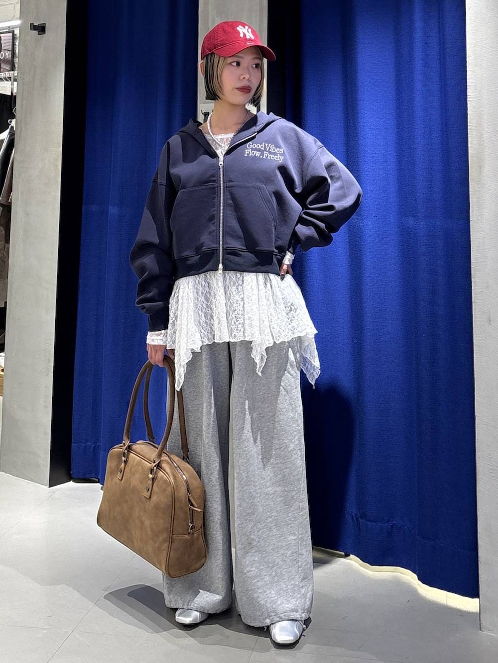 イエロー系のボストンバッグ、ブルー系のパーカー、グレー系のスウェットパンツを着用したレディースの冬コーディネートの3枚目の写真