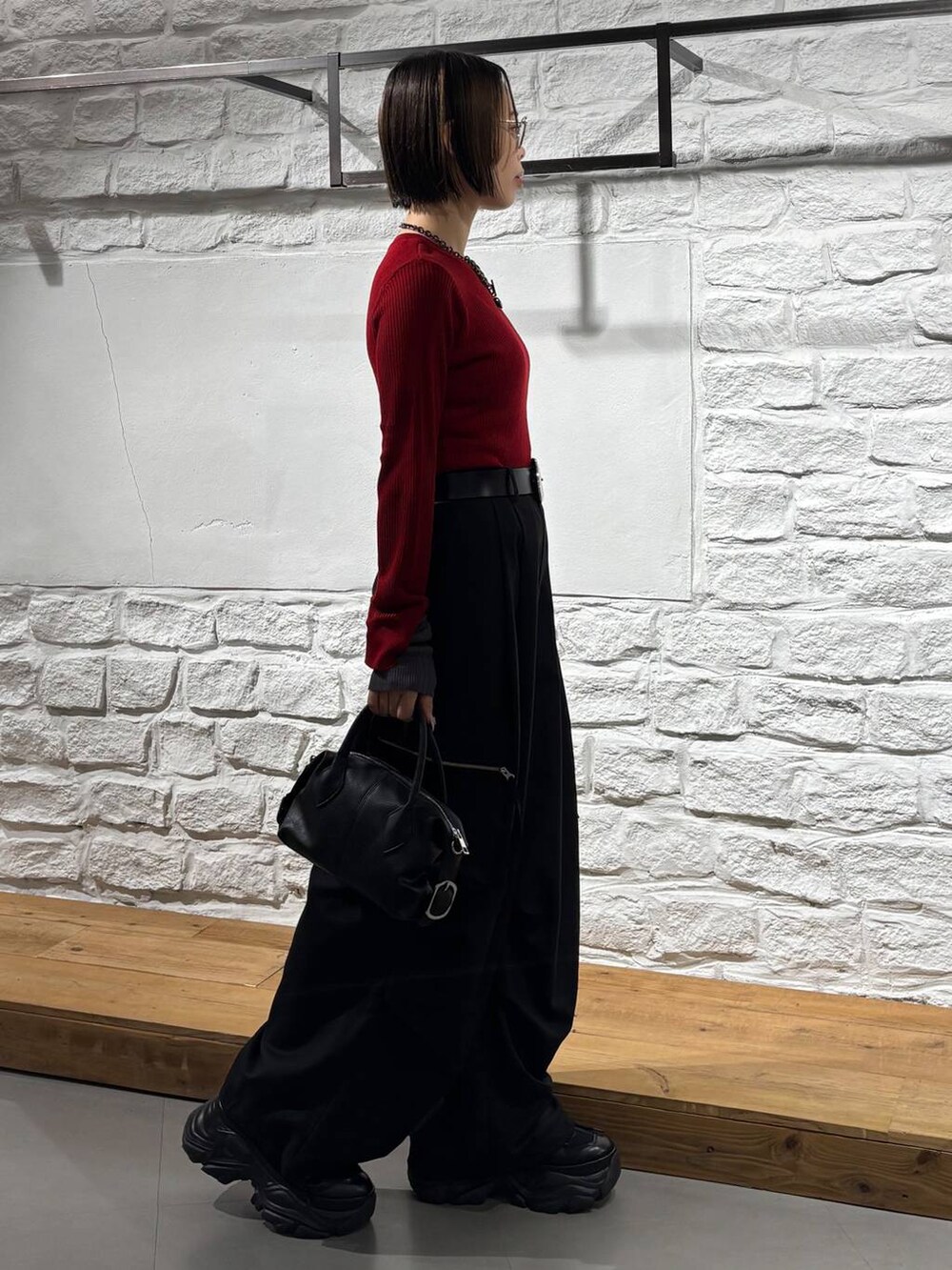 ブラック系のカーゴパンツ、レッド系のニット/セーター、ブラック系のスニーカーを着用したレディースの秋コーディネートの5枚目の写真