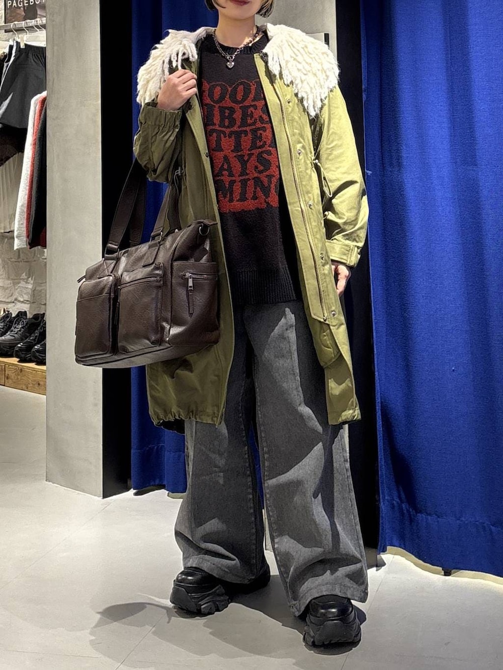 ブラック系のスニーカー、ブラウン系のボストンバッグ、ブラック系のニット/セーターを着用したレディースの冬コーディネートの2枚目の写真