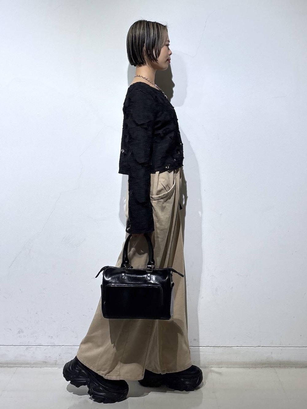 ブラック系のスニーカー、ブラック系のショルダーバッグ、ブラウン系のスウェットパンツを着用したレディースの冬コーディネートの4枚目の写真