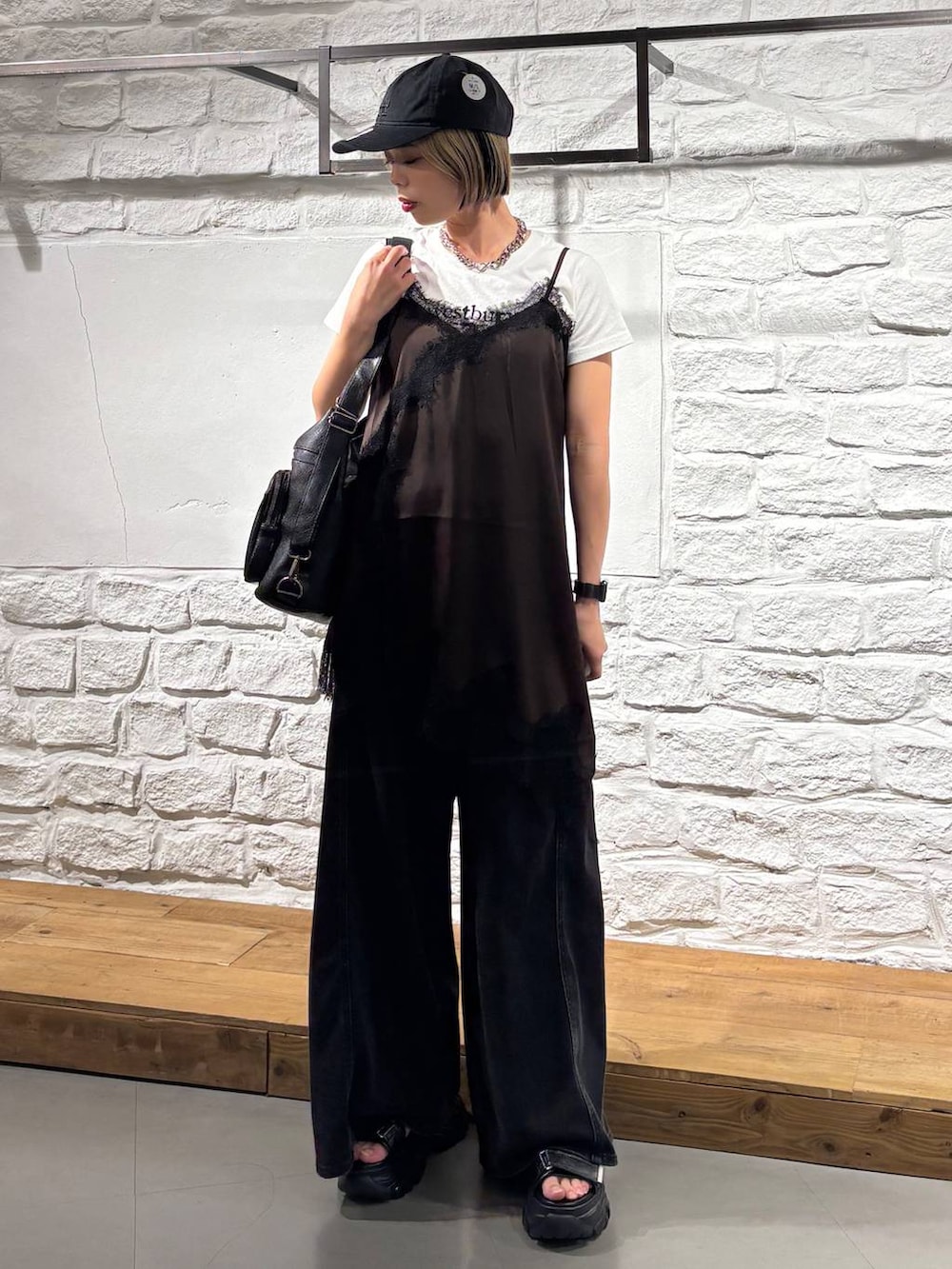 ブラック系のデニムパンツ、ブラウン系のチュニック、ホワイト系のTシャツ/カットソーを着用したレディースの夏コーディネートの2枚目の写真