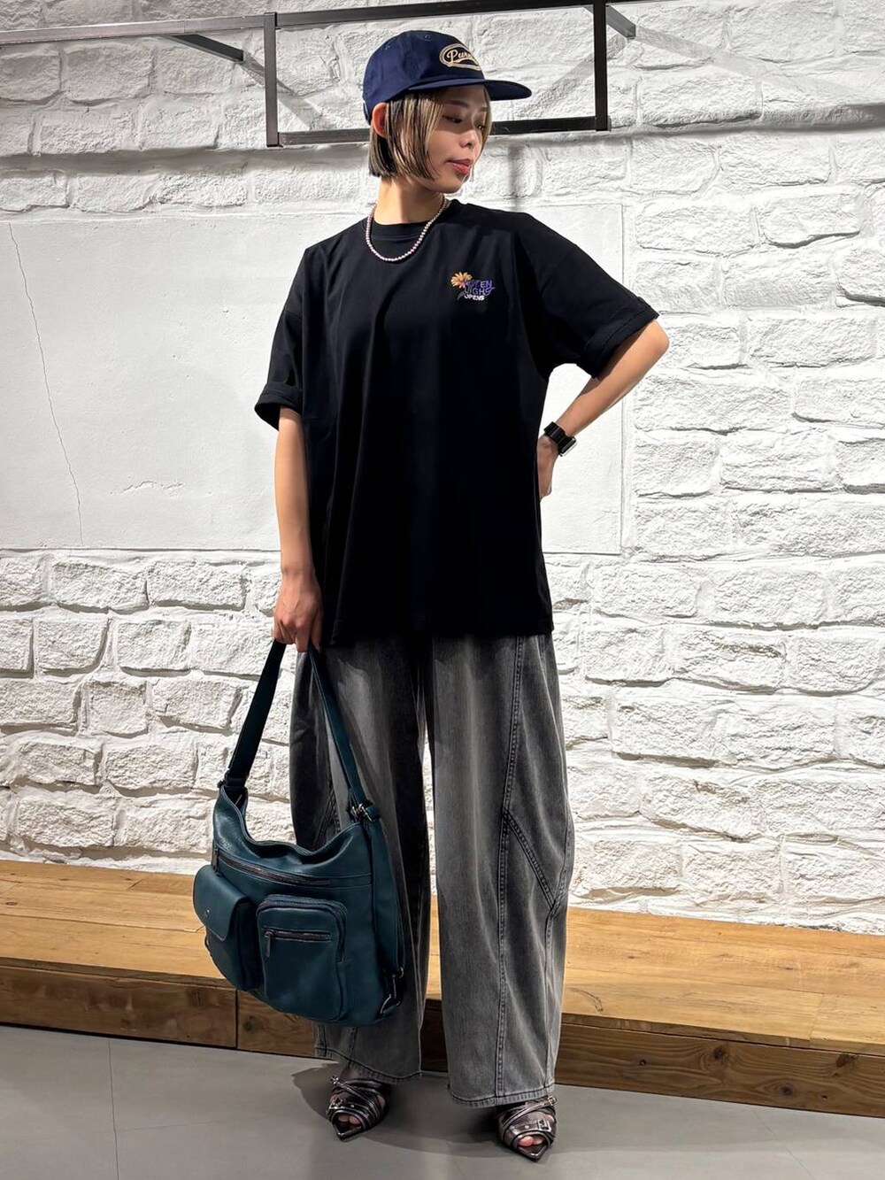 ブルー系のショルダーバッグ、ブラック系のデニムパンツ、イエロー系のサンダルを着用したレディースの春コーディネートの2枚目の写真