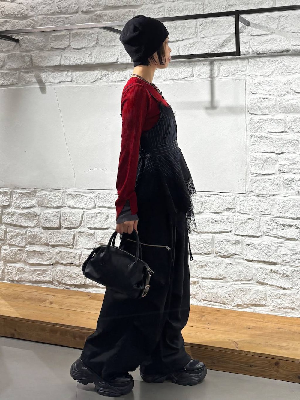 ブラック系のカーゴパンツ、レッド系のニット/セーター、ブラック系のスニーカーを着用したレディースの秋コーディネートの5枚目の写真