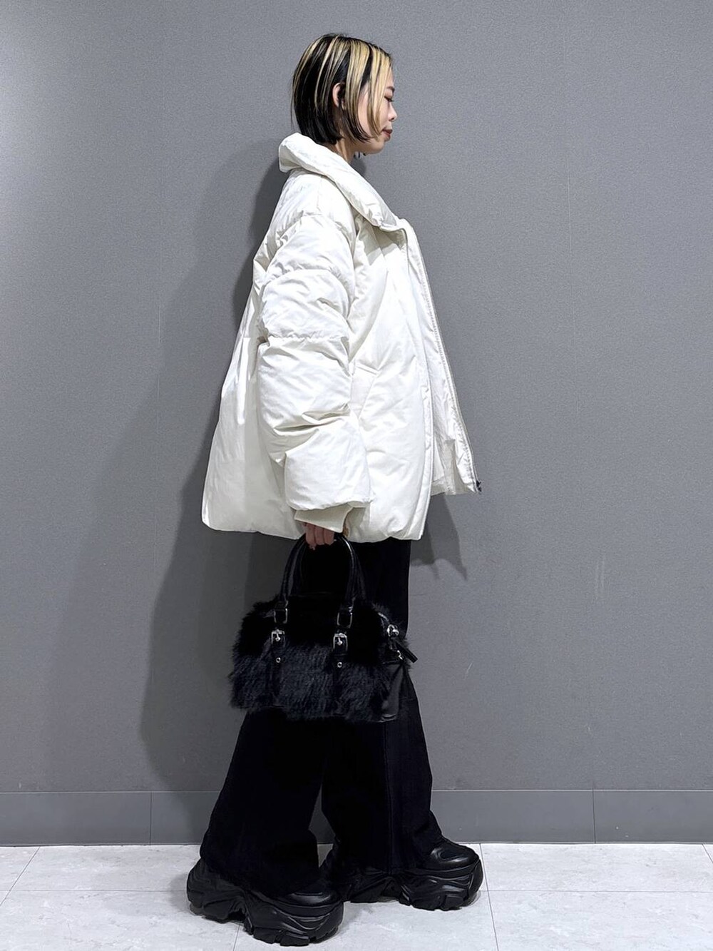 ブラック系のブーツ、ブラック系のデニムパンツ、ホワイト系のブルゾンを着用したレディースの冬コーディネートの3枚目の写真