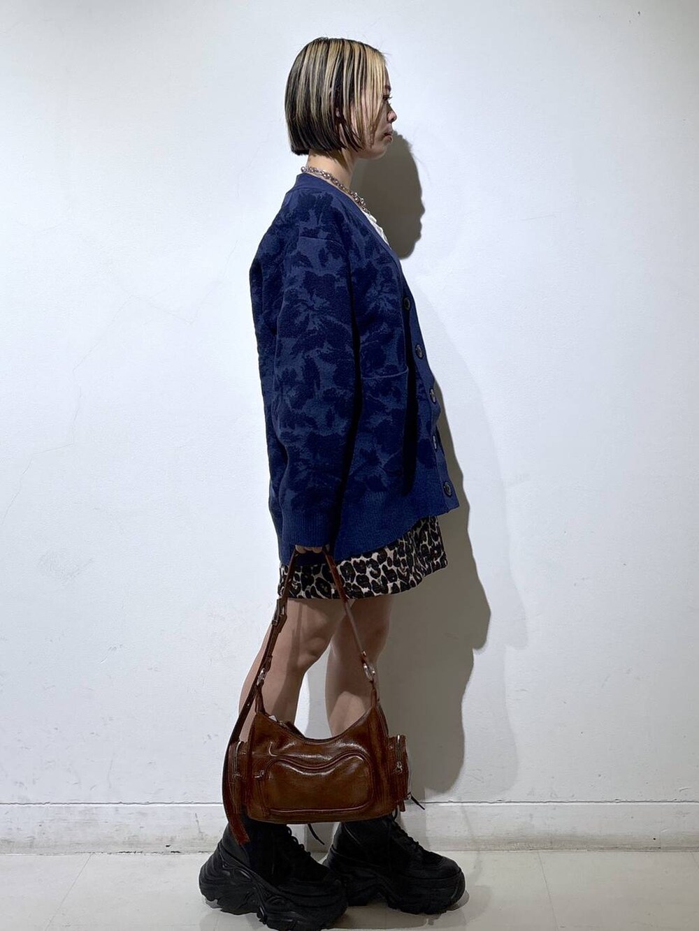 ブラック系のブーツ、ホワイト系のTシャツ/カットソー、ブラウン系のスカートを着用したレディースの秋コーディネートの3枚目の写真