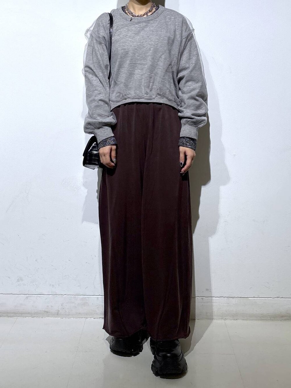 ブラック系のブーツ、シルバー系のTシャツ/カットソー、ブラウン系のスウェットパンツを着用したレディースの秋コーディネートの2枚目の写真