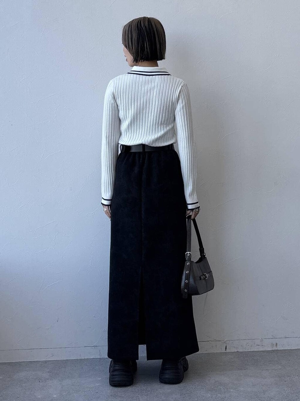 グレー系のスニーカー、ブラック系のスカート、ホワイト系のニット/セーターを着用したレディースの冬コーディネートの6枚目の写真