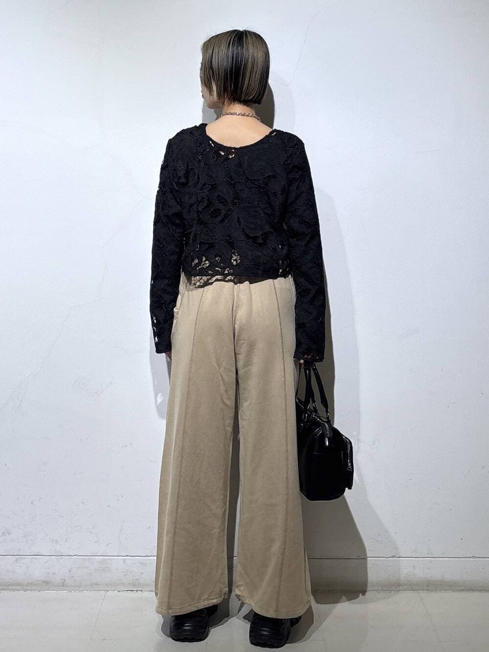 ブラック系のスニーカー、ブラック系のショルダーバッグ、ブラウン系のスウェットパンツを着用したレディースの冬コーディネートの5枚目の写真