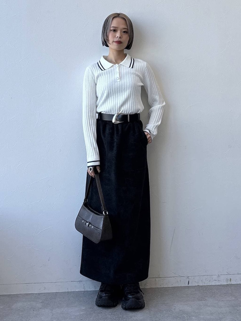 グレー系のスニーカー、ブラック系のスカート、ホワイト系のニット/セーターを着用したレディースの冬コーディネートの4枚目の写真