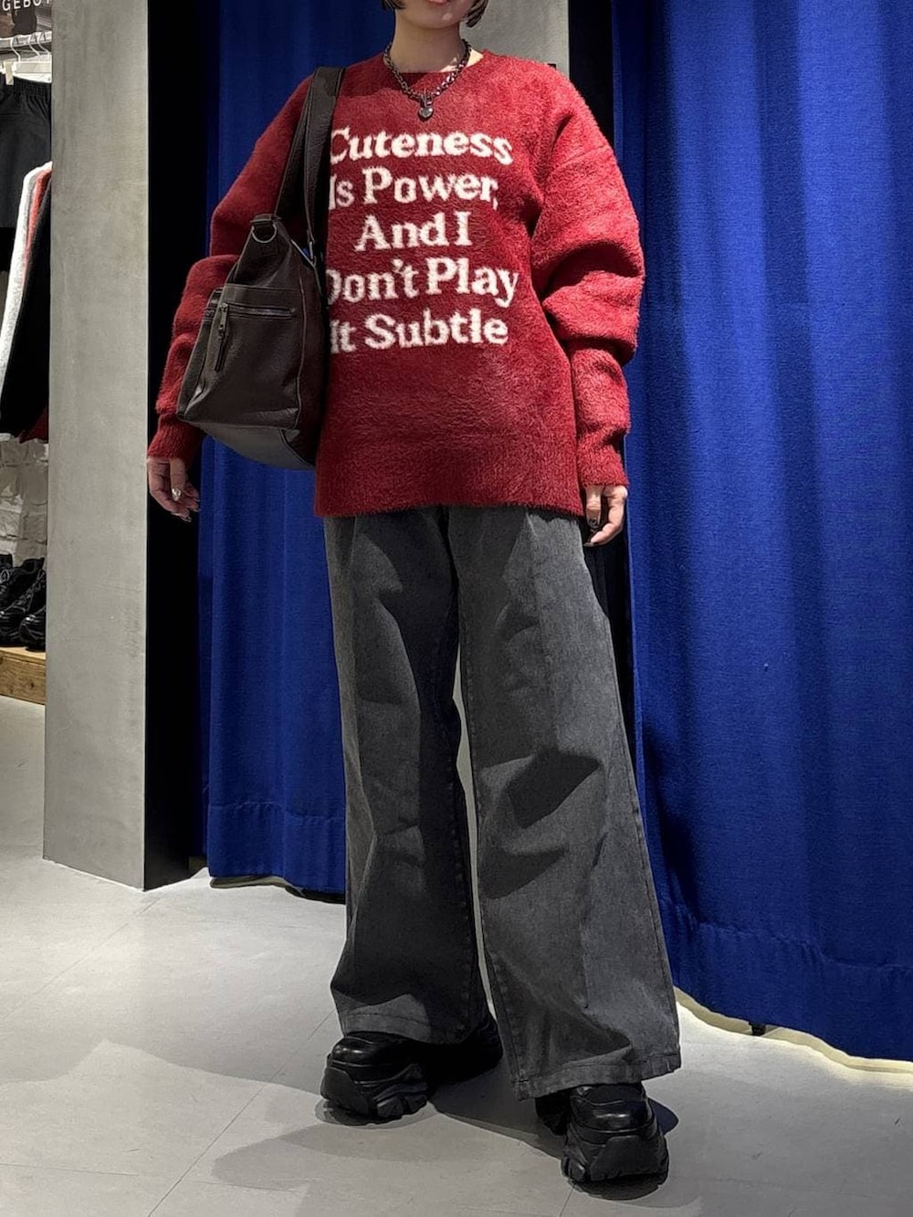 ブラック系のブーツ、ブラウン系のボストンバッグ、レッド系のニット/セーターを着用したレディースの冬コーディネートの2枚目の写真