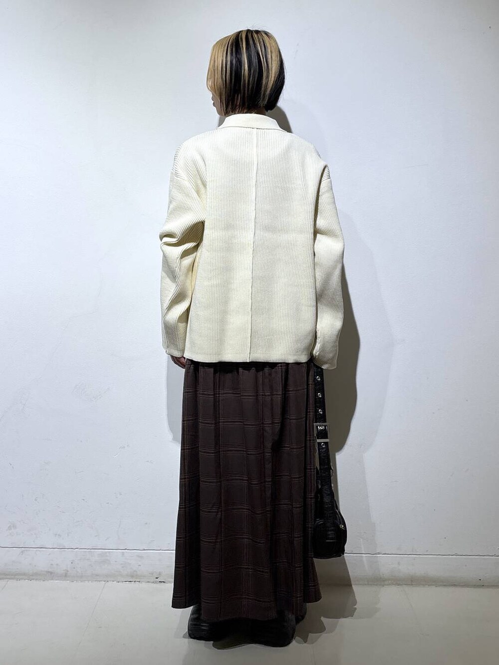 ブラック系のブーツ、ホワイト系のブルゾン、ブラウン系のスカートを着用したレディースの冬コーディネートの4枚目の写真