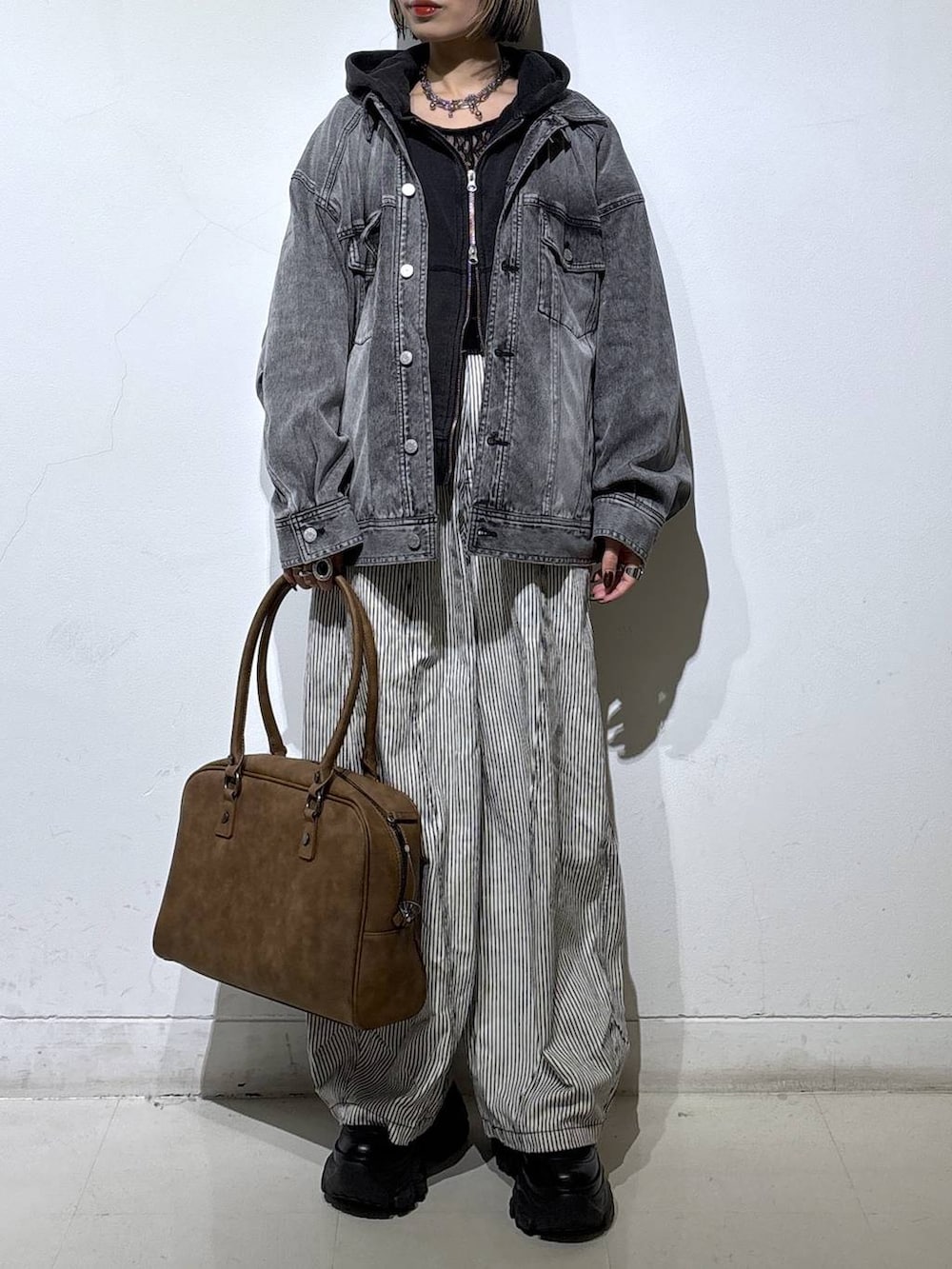 ブラック系のブーツ、ベージュ系のボストンバッグ、ブラック系のTシャツ/カットソーを着用したレディースの冬コーディネートの2枚目の写真