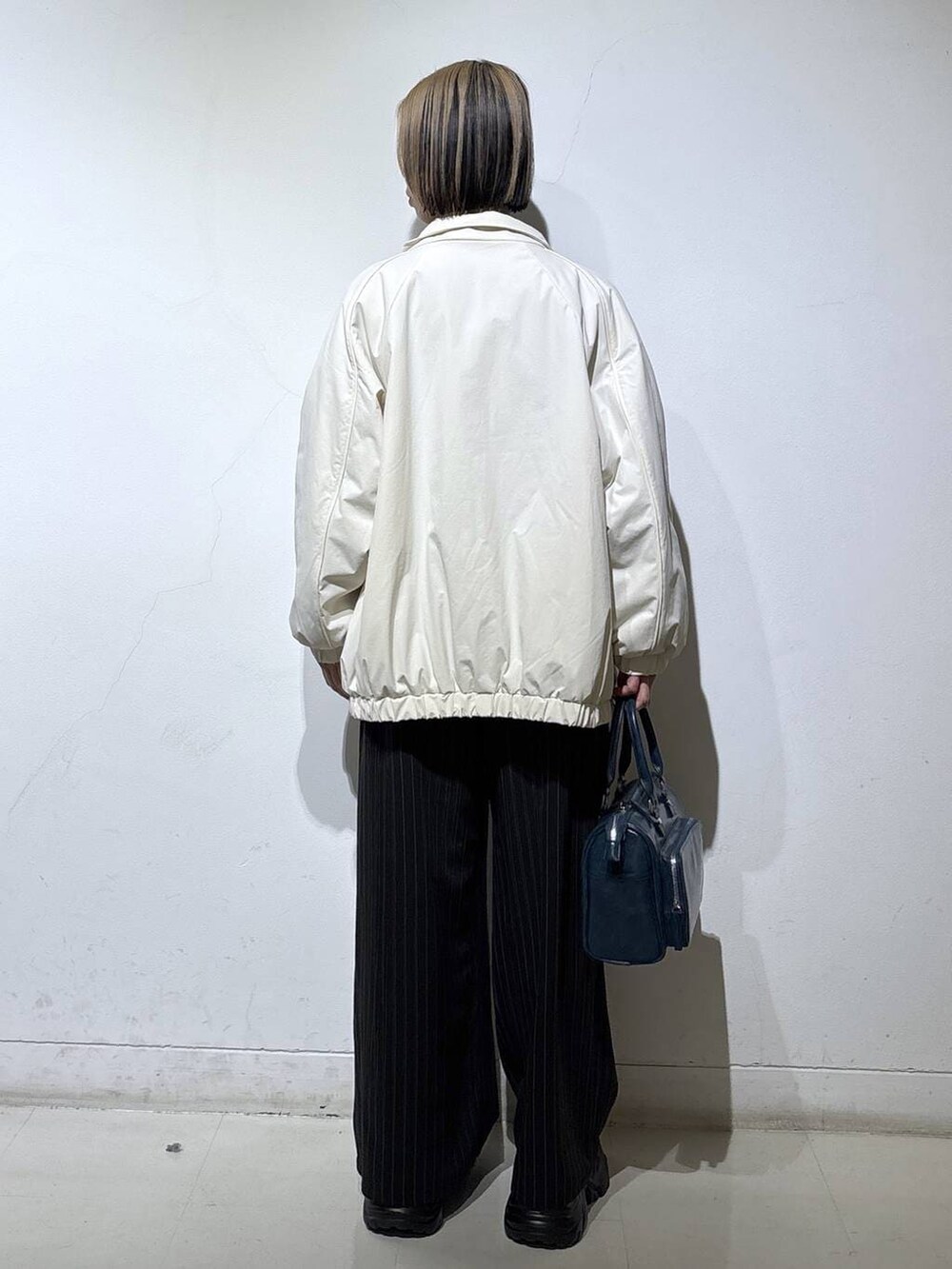 ブラック系のスニーカー、ホワイト系のナイロンジャケット、ブルー系のショルダーバッグを着用したレディースの冬コーディネートの5枚目の写真