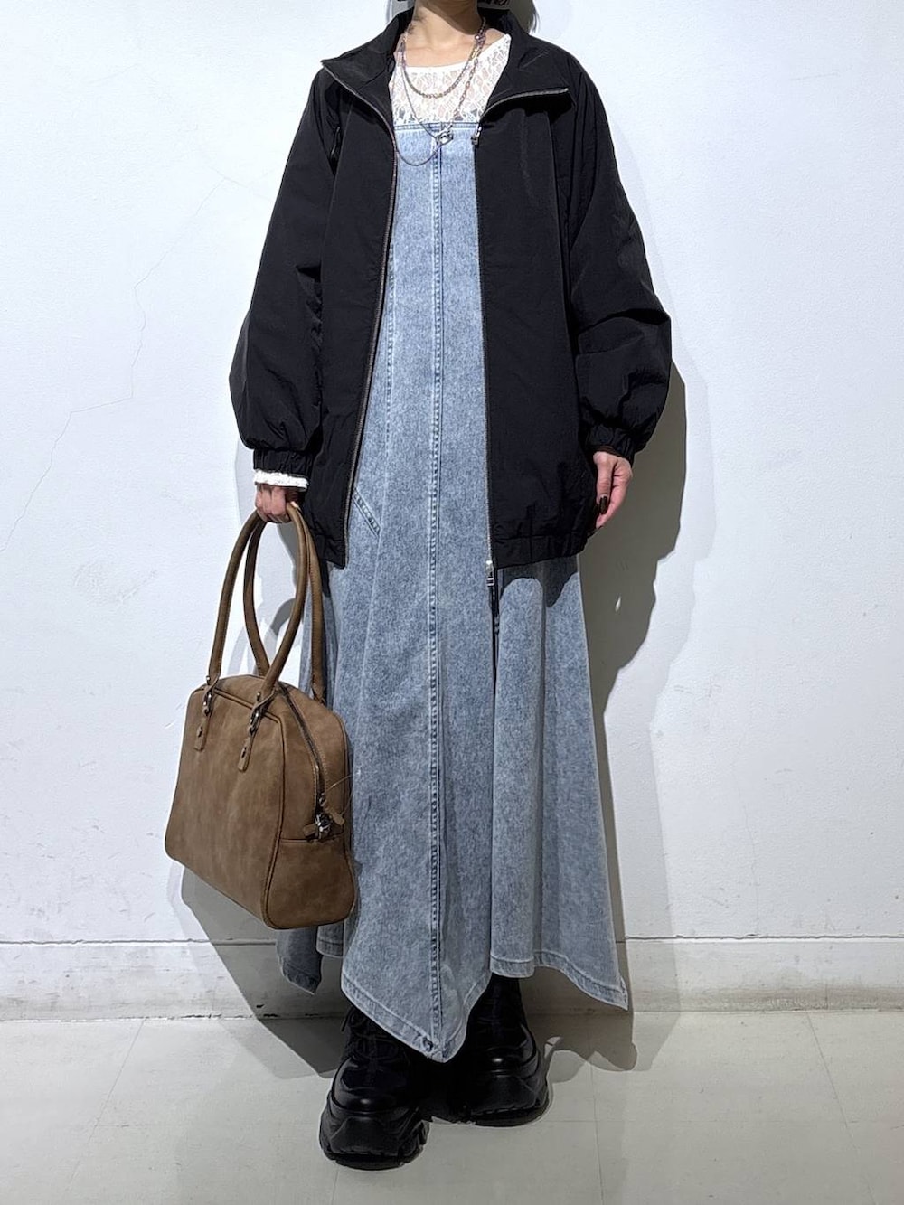 ブラック系のブーツ、ベージュ系のボストンバッグ、ブラック系のナイロンジャケットを着用したレディースの春コーディネートの2枚目の写真