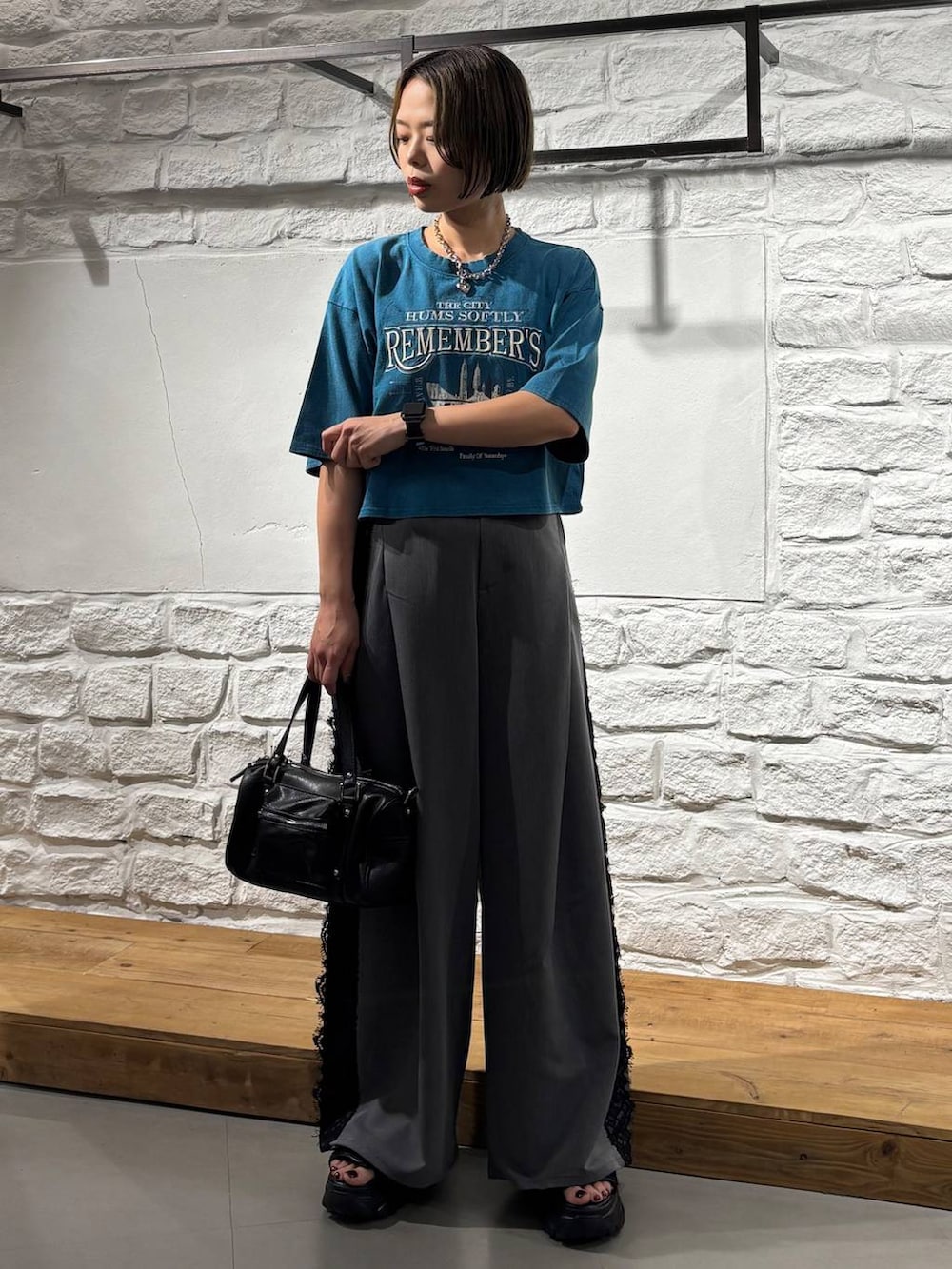 ブラック系のショルダーバッグ、ブルー系のTシャツ/カットソー、ブラック系のサンダルを着用したレディースの夏コーディネートの2枚目の写真