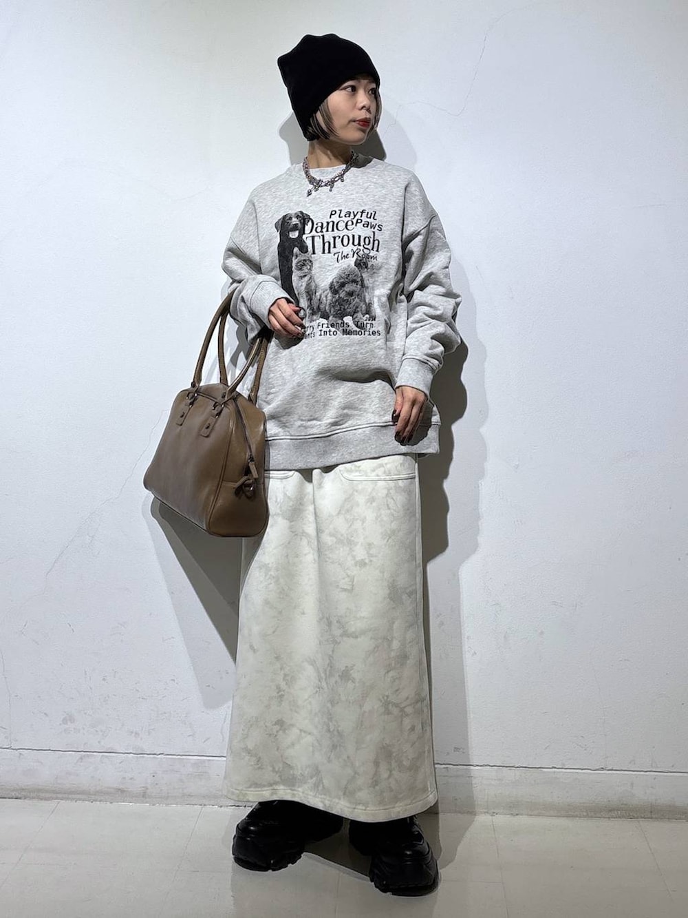 ブラック系のスニーカー、ベージュ系のボストンバッグ、ホワイト系のスカートを着用したレディースの冬コーディネートの3枚目の写真