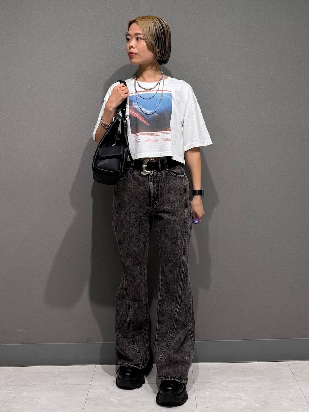 ブラック系のスニーカー、ブラック系のデニムパンツ、ホワイト系のTシャツ/カットソーを着用したレディースの春コーディネートの2枚目の写真