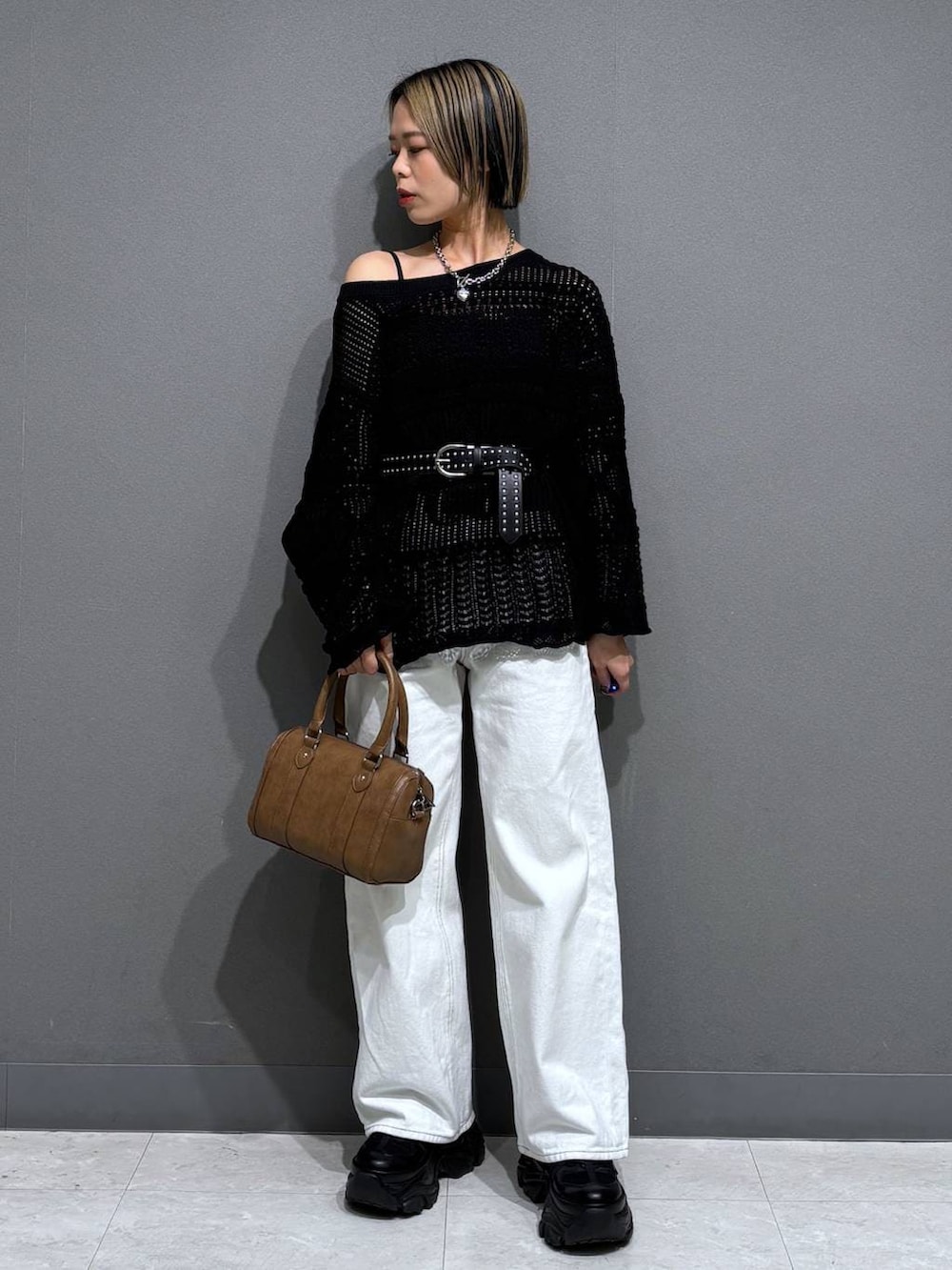 ブラック系のスニーカー、ブラック系のキャミソール、ホワイト系のスラックスを着用したレディースの春コーディネートの2枚目の写真