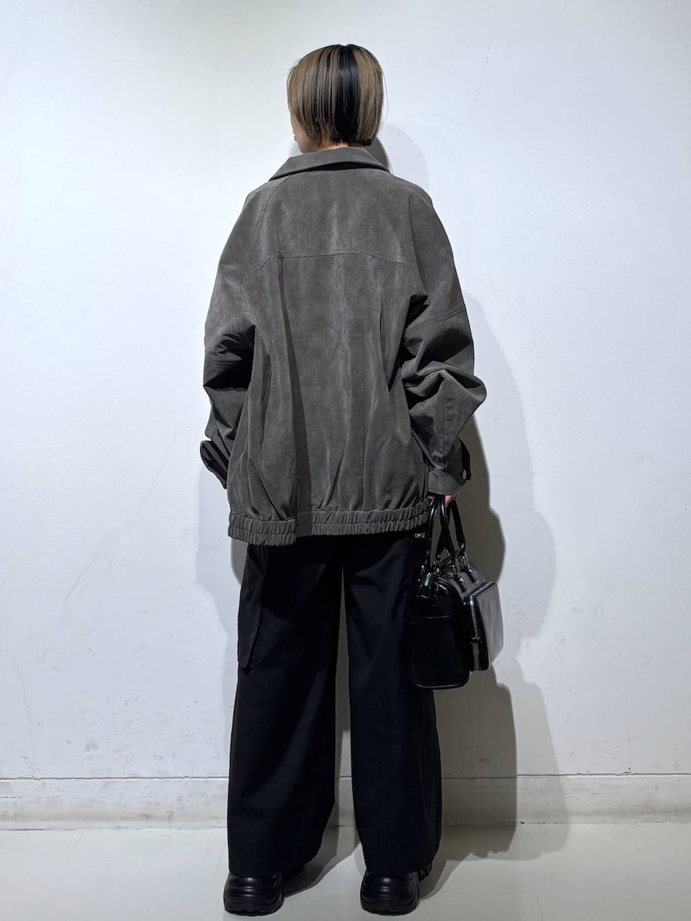 ブラック系のスニーカー、ブラック系のショルダーバッグ、グレー系のブルゾンを着用したレディースの春コーディネートの5枚目の写真