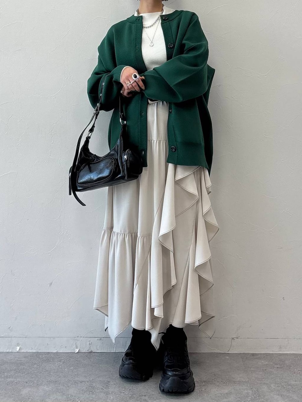 ブラック系のスニーカー、ブラック系のショルダーバッグ、ホワイト系のニット/セーターを着用したレディースの冬コーディネートの2枚目の写真