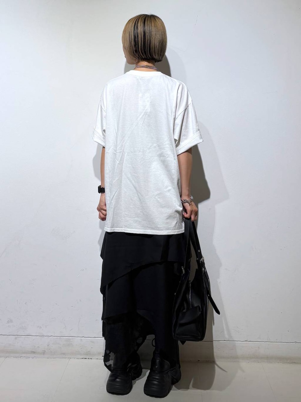 ブラック系のブーツ、ホワイト系のTシャツ/カットソー、ブラック系のハンドバッグを着用したレディースの夏コーディネートの5枚目の写真