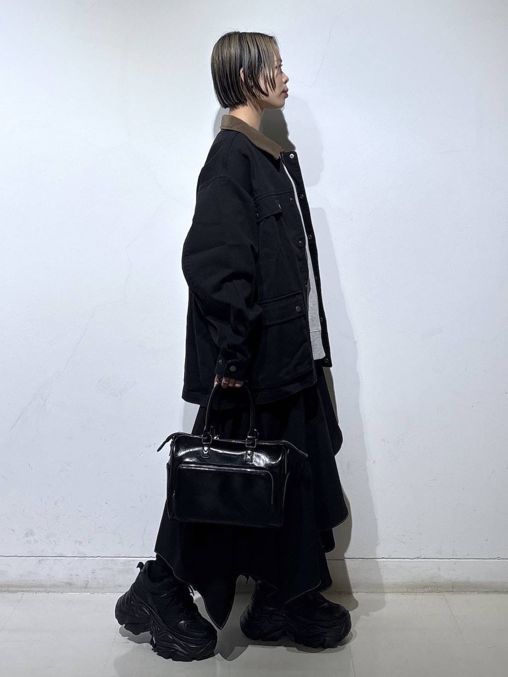 ブラック系のブーツ、グレー系のスウェット、ブラック系のスカートを着用したレディースの春コーディネートの3枚目の写真