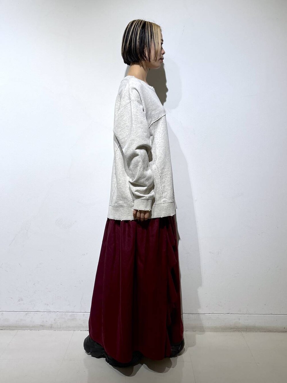 ブラック系のブーツ、ベージュ系のスウェット、レッド系のスカートを着用したレディースの秋コーディネートの3枚目の写真