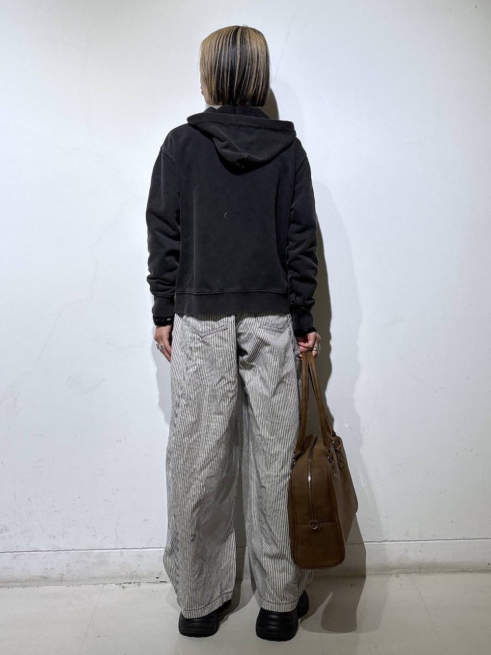 ブラック系のブーツ、ベージュ系のボストンバッグ、ブラック系のTシャツ/カットソーを着用したレディースの冬コーディネートの6枚目の写真