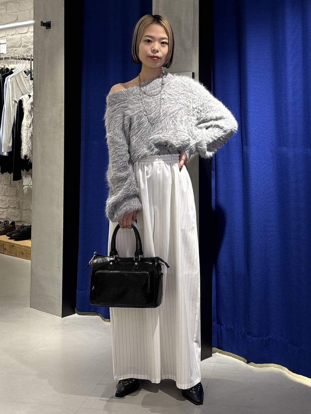 グレー系のニット/セーター、ブラック系のショルダーバッグ、ブラック系のサンダルを着用したレディースの冬コーディネートの3枚目の写真