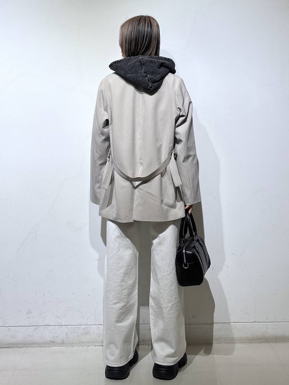 ブラック系のブーツ、ブラック系のTシャツ/カットソー、ホワイト系のスラックスを着用したレディースの冬コーディネートの5枚目の写真