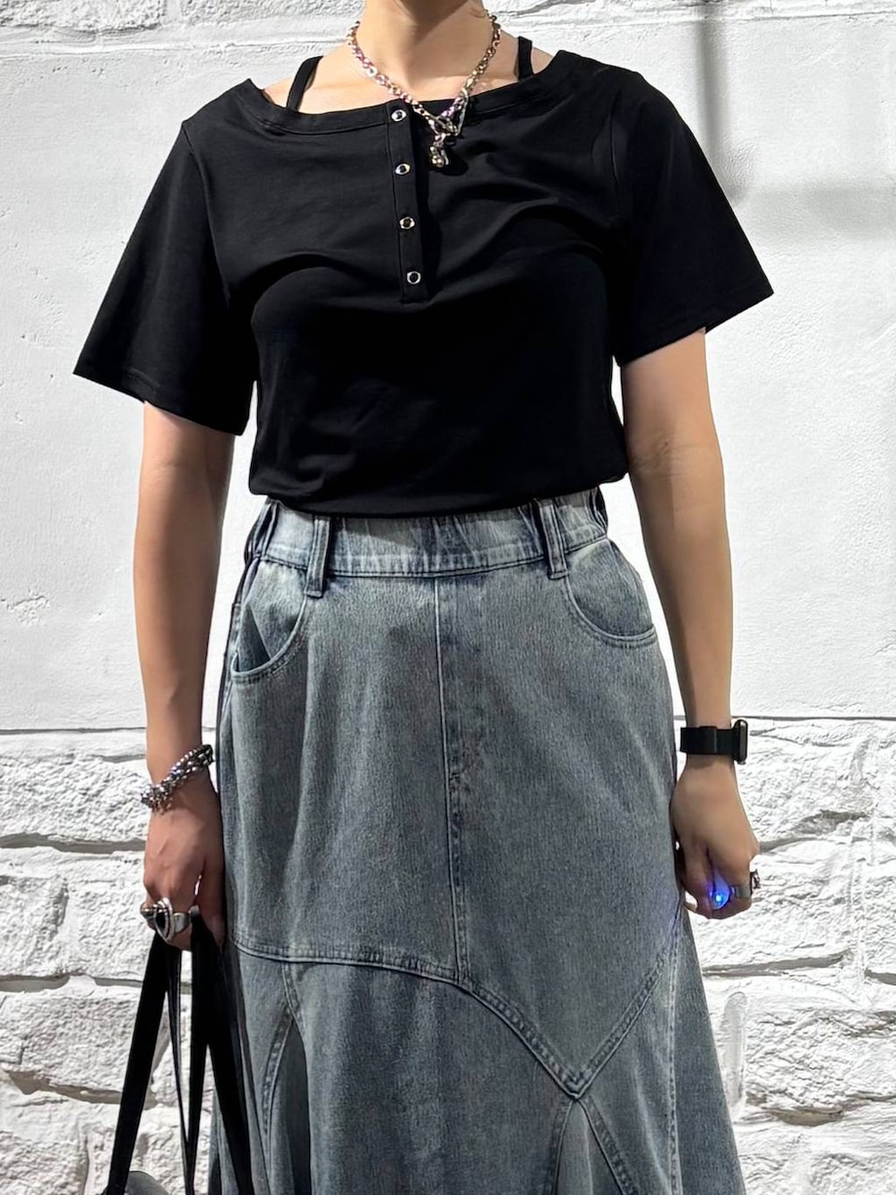 ブラック系のTシャツ/カットソー、ブルー系のデニムスカート、ブラック系のショルダーバッグを着用したレディースの夏コーディネートの4枚目の写真