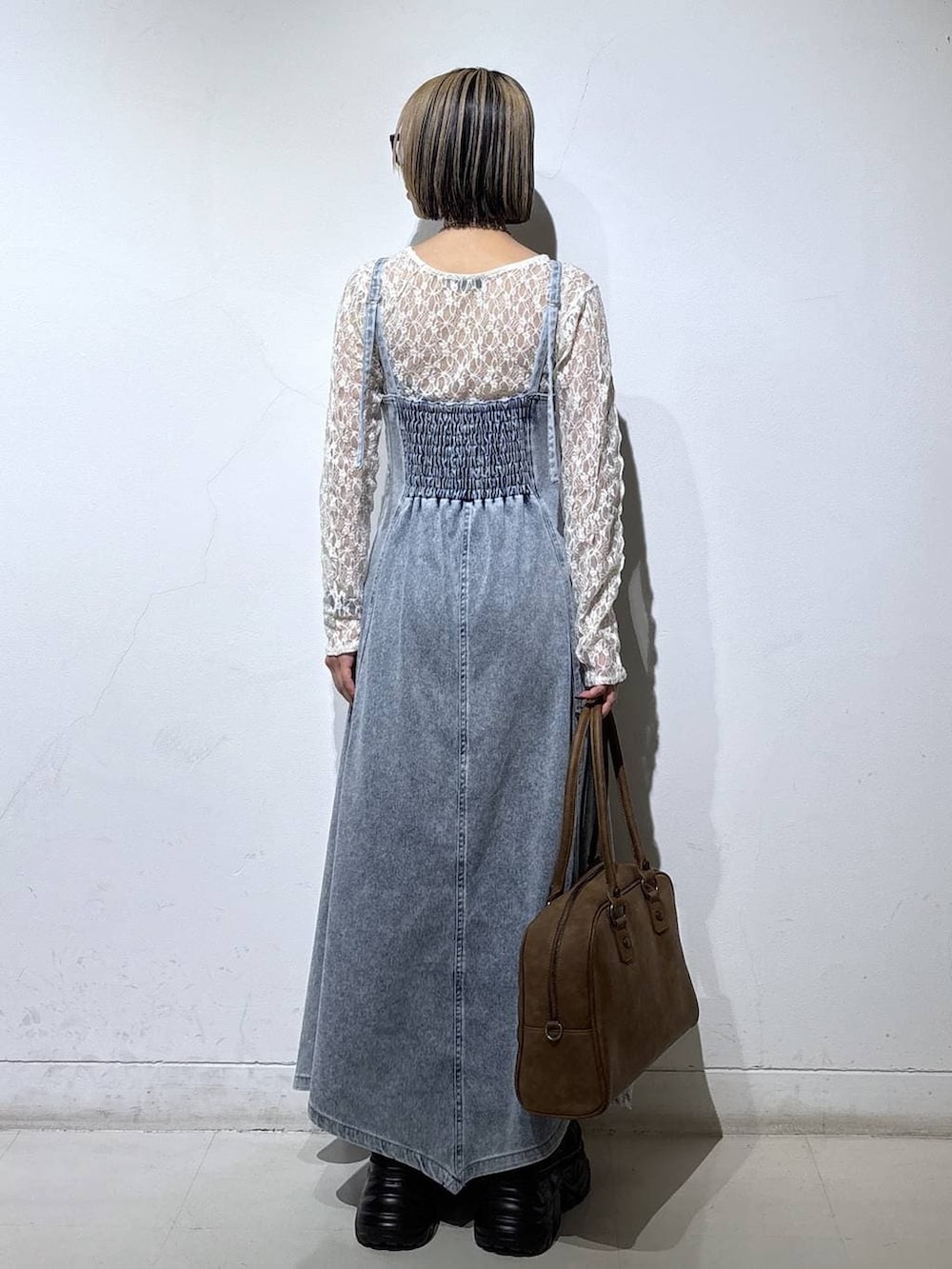 ブラック系のブーツ、ベージュ系のボストンバッグ、ブルー系のワンピースを着用したレディースの冬コーディネートの4枚目の写真