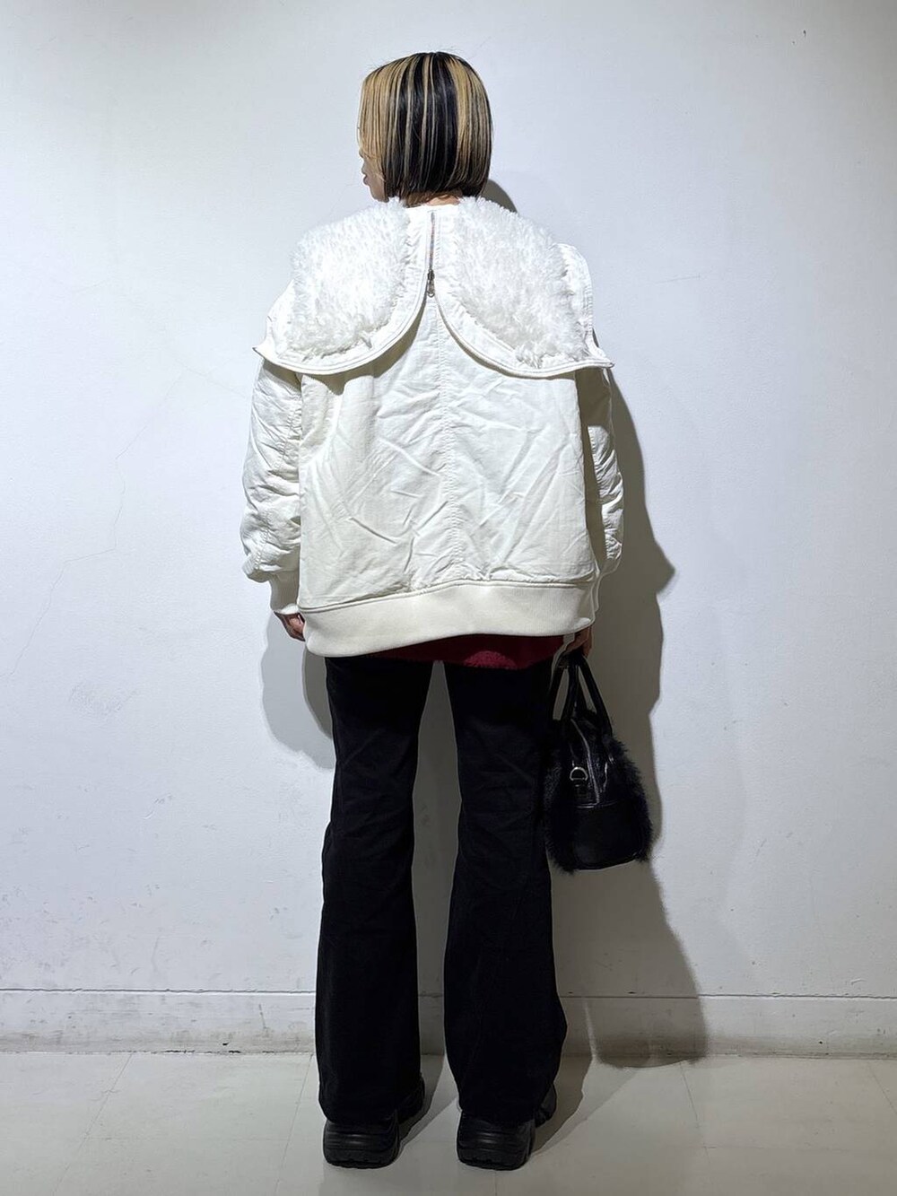 ブラック系のブーツ、ブラック系のデニムパンツ、ホワイト系のブルゾンを着用したレディースの冬コーディネートの4枚目の写真