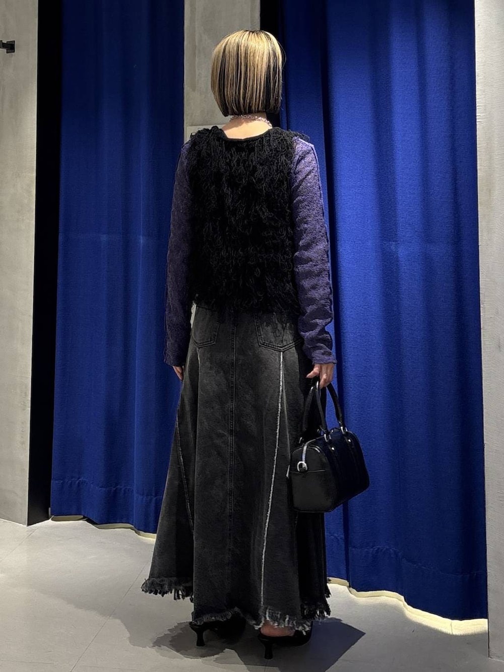 ブラック系のボストンバッグ、ブラック系のサンダル、ブラック系のデニムスカートを着用したレディースの冬コーディネートの5枚目の写真